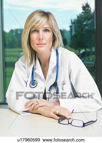 Stock Photo - Portrait of female doctor at her desk.. Fotosearch