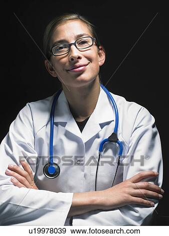Portrait of smiling female doctor at her desk working late looking at camera. View Large Photo Image Stock Photo - Portrait of smiling female doctor at her desk working late looking at camera.. Fotosearch