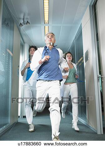 Three doctors running in a lobby of a hospital. View Large Photo Image Stock Image - Three doctors running in a lobby of a hospital.. Fotosearch