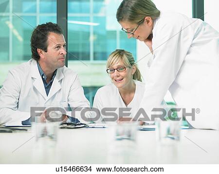 Picture - Three doctors smiling and talking in a meeting.. Fotosearch