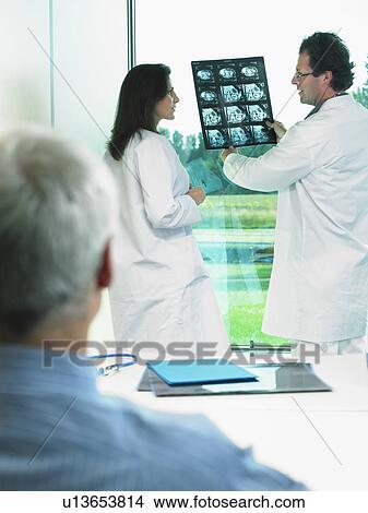 Two doctors discussing x-rays with mature patient. View Large Photo Image Picture - Two doctors discussing x-rays with mature patient.. Fotosearch