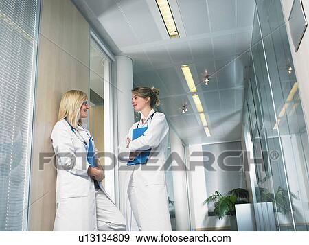 Two female doctors in discussion in a lobby of a hospital. View Large Photo Image Stock Photo - Two female doctors in discussion in a lobby of a hospital.. Fotosearch