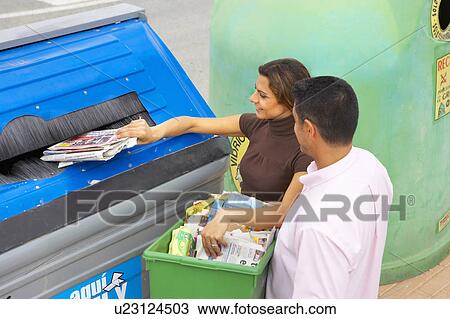 Stock Image - High angle view of couple placing papers in a recycle bin, husband holding box full of papers, Alicante, Spain,. Fotosearch