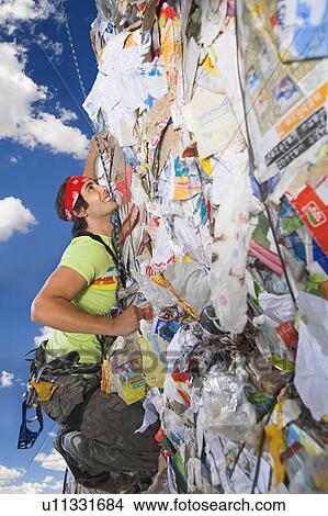 Man climbing a wall of recycling. View Large Photo Image Picture - Man climbing a wall of recycling.. Fotosearch