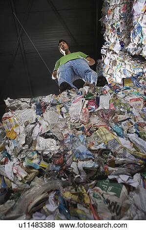 Stock Photo - Man standing on top of a wall of recycling.. Fotosearch