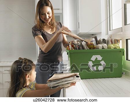 Stock Photo - Mother and daughter (4-6) sharing recycling duties in domestic kitchen. Fotosearch
