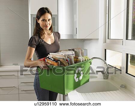 Stock Image - Woman holding recycling box, smiling, portrait. Fotosearch