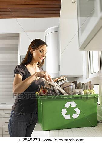 Stock Photo - Woman putting newspapers in recycling box. Fotosearch