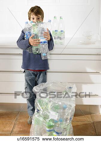 Stock Photography - Young boy holding an armful of recyclable plastic bottles, portrait. Fotosearch