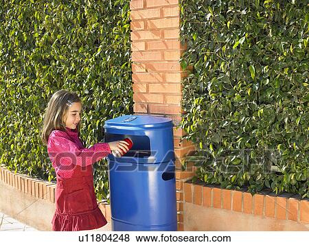 Stock Photo - Young girl (5-7) putting can in public bin, Alicante, Spain,. Fotosearch