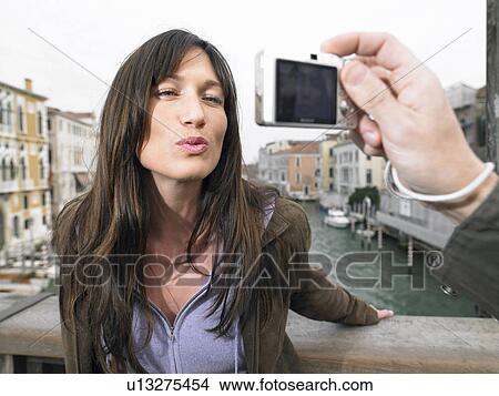 Picture - Italy, Venice, woman blowing kiss to camera held by man. Fotosearch