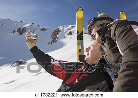 Mature man in ski-wear taking self portrait of himself and wife on mountain View Large Photo Image Stock Image - Mature man in ski-wear taking self portrait of himself and wife on mountain. Fotosearch