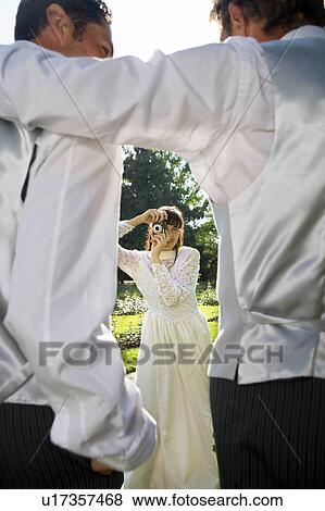 Young bride photographing groom and father in gardens View Large Photo Image Stock Photo - Young bride photographing groom and father in gardens. Fotosearch