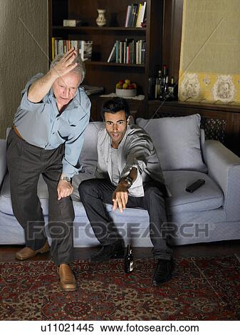 Stock Photography - Senior father and son watching television, gesticulating. Fotosearch