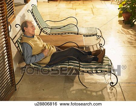 Senior man lying on sun lounger on terrace, smiling View Large Photo Image Stock Photograph - Senior man lying on sun lounger on terrace, smiling. Fotosearch