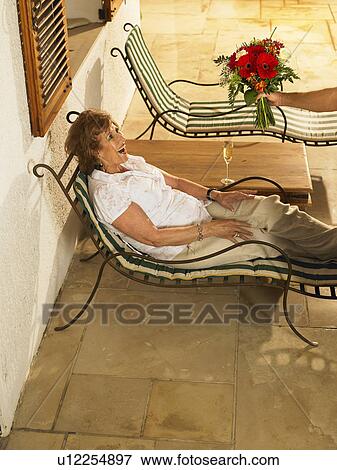 Senior woman lying on sun lounger on terrace, smiling View Large Photo Image Stock Photo - Senior woman lying on sun lounger on terrace, smiling. Fotosearch