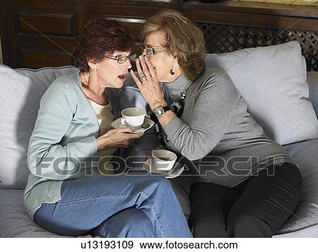 Two senior women gossiping over a cup of tea on sofa. Alicante, Spain. View Large Photo Image Stock Photo - Two senior women gossiping over a cup of tea on sofa. Alicante, Spain.. Fotosearch
