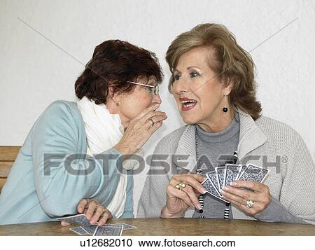 Two senior women playing cards, whispering View Large Photo Image Stock Image - Two senior women playing cards, whispering. Fotosearch