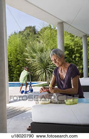 Stock Image - Woman peeling fruit boy in background.. Fotosearch