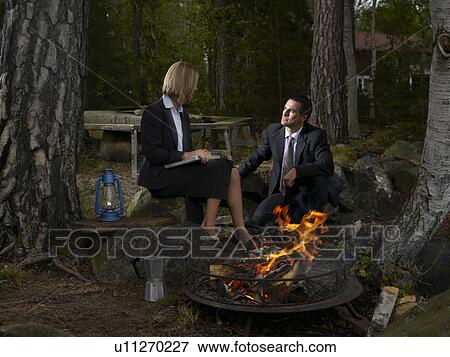 Stock Photo - Business meeting by a camp fire. Fotosearch