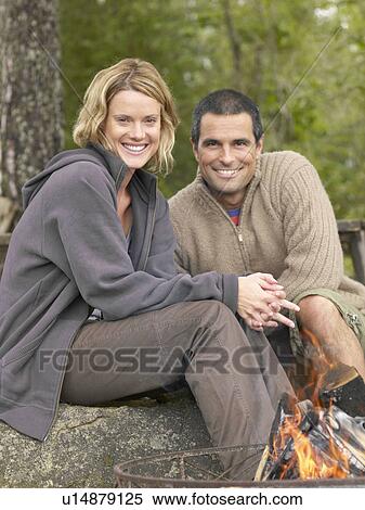 Stock Photography - Couple by a fire pit smiling.. Fotosearch