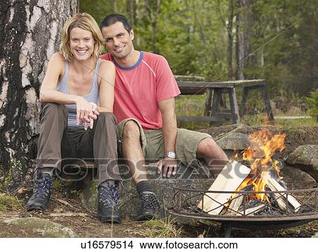 Couple sitting by a fire pit smiling. View Large Photo Image Picture - Couple sitting by a fire pit smiling.. Fotosearch