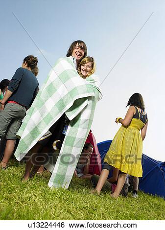 Stock Photograph - Couple Wrapped up in blanket by tents. Fotosearch