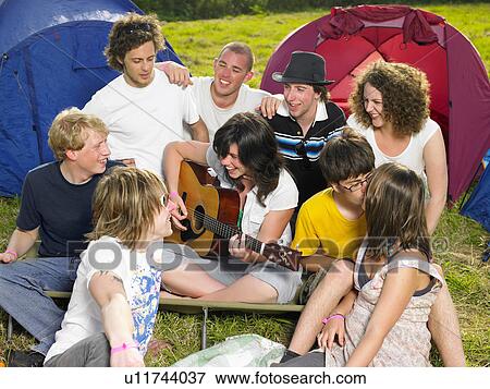 Stock Photo - Group outside tent one girl playing a guitar. Fotosearch