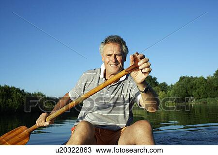 Stock Image - Man rowing a canoe.. Fotosearch