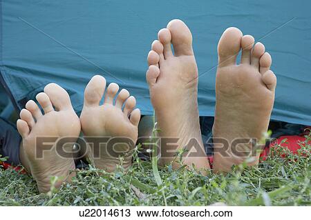 Stock Image - Two people's feet sticking out of tent door.. Fotosearch