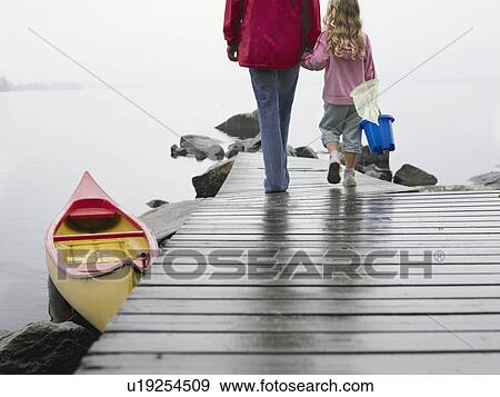 Woman and young girl holding hands walking on a dock. View Large Photo Image Stock Photo - Woman and young girl holding hands walking on a dock.. Fotosearch