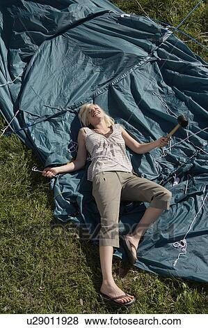 Woman holding mallet lying on tent smiling. View Large Photo Image Stock Photo - Woman holding mallet lying on tent smiling.. Fotosearch