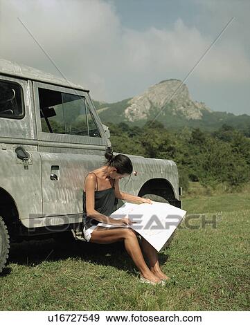 Woman sitting by SUV with a compass and map. View Large Photo Image Stock Photo - Woman sitting by SUV with a compass and map.. Fotosearch