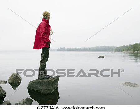 Woman standing on large rock in the water. View Large Photo Image Stock Photograph - Woman standing on large rock in the water.. Fotosearch
