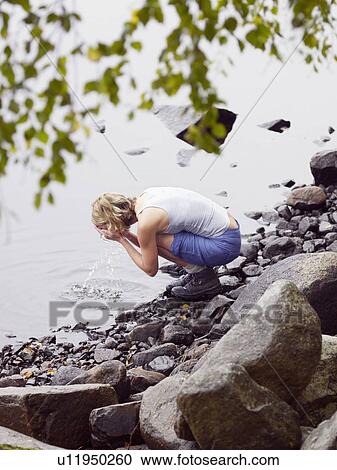 Stock Image - Woman washing face in lake.. Fotosearch