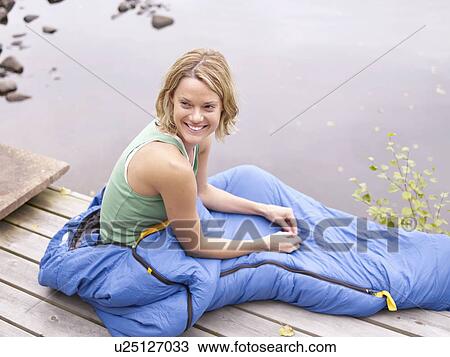 Woman with sleeping bag around waist sitting on dock smiling. View Large Photo Image Stock Image - Woman with sleeping bag around waist sitting on dock smiling.. Fotosearch