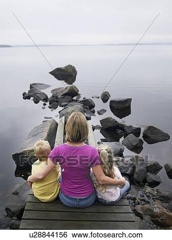 Woman with young boy and young girl sitting on a dock by a lake. View Large Photo Image Stock Photograph - Woman with young boy and young girl sitting on a dock by a lake.. Fotosearch
