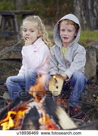 Stock Photo - Young boy and young girl cooking toast over a fire at a campsite.. Fotosearch