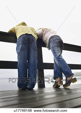 Young boy and young girl leaning over a railing by a lake. View Large Photo Image Stock Photo - Young boy and young girl leaning over a railing by a lake.. Fotosearch