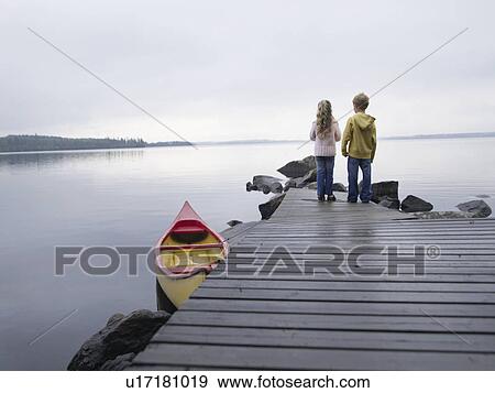 Young girl and young boy standing on a dock near a boat. View Large Photo Image Stock Photo - Young girl and young boy standing on a dock near a boat.. Fotosearch