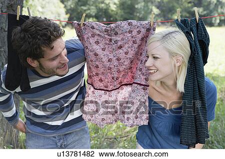 Couple peeking through laundry hanging on clothesline smiling. View Large Photo Image Stock Image - Couple peeking through laundry hanging on clothesline smiling.. Fotosearch