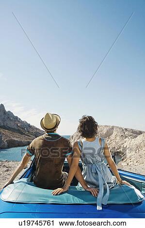 Man and woman sitting on car. View Large Photo Image Stock Image - Man and woman sitting on car.. Fotosearch