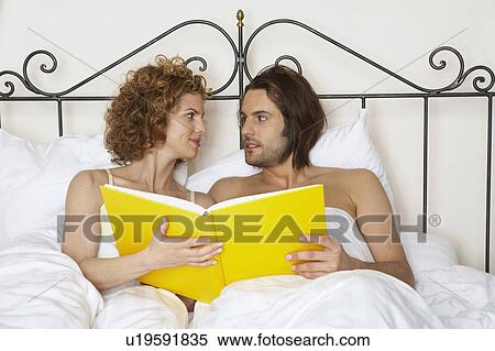 young couple in bed holding yellow book View Large Photo Image Stock Photography - young couple in bed holding yellow book. Fotosearch