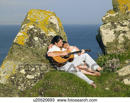 Young couple on a cliff playing guitar. View Large Photo Image Stock Image - Young couple on a cliff playing guitar.. Fotosearch