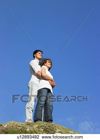 Stock Image - Young couple on a large rock.. Fotosearch