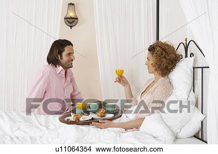 Picture - Young couple sharing breakfast in bed. Fotosearch