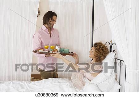 young man smiling passing breakfast tray to woman in bed View Large Photo Image Stock Photo - young man smiling passing breakfast tray to woman in bed. Fotosearch