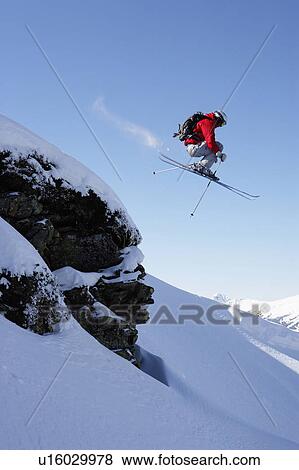 Stock Photo - Austria, Saalbach, male skier jumping over rock on snow covered slope. Fotosearch