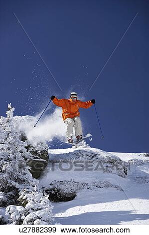 Austria, Saalbach, male skier jumping over mound past trees on slope View Large Photo Image Stock Photo - Austria, Saalbach, male skier jumping over mound past trees on slope. Fotosearch