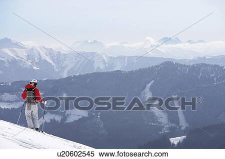 Stock Photography - Austria, Saalbach, male skier standing on slope, mountains in distance. Fotosearch